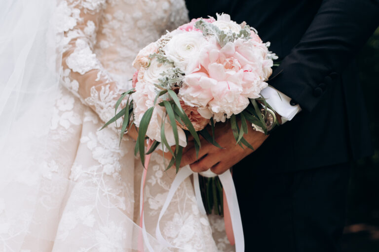 Frontview of groom and brides hands together are holding wedding