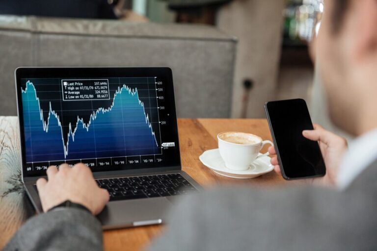 cropped-image-businessman-sitting-by-table-cafe-analyzing-indicators-laptop-computer-while-using-smartphone_171337-5599