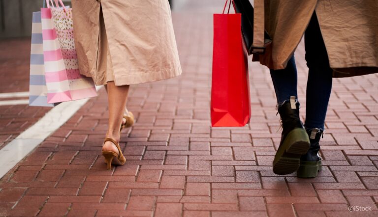 Rear view of two unrecognizable women walking outdoors holding shopping bags