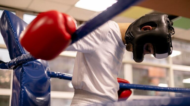 male-boxer-with-helmet-gloves-ring-practicing_23-2148759704