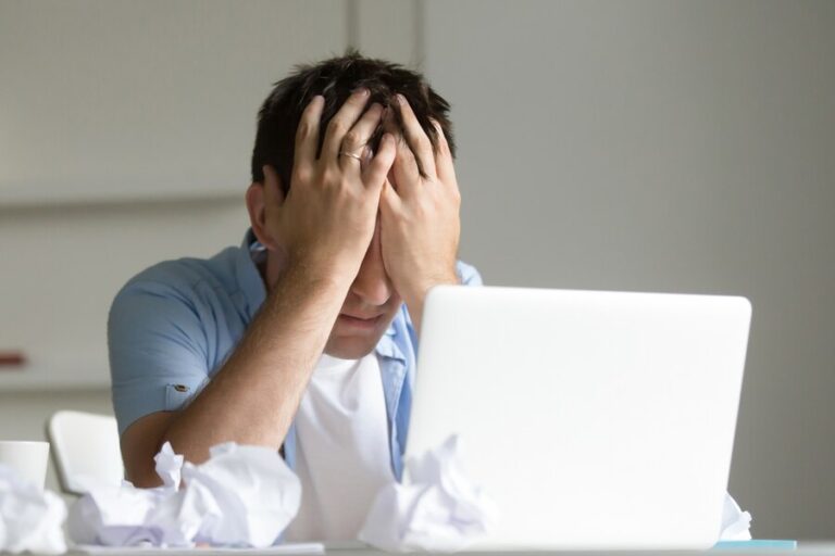 portrait-man-near-laptop-his-hands-closing-his-face_1163-2128